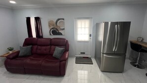 A modern living room with a red sofa, a stainless steel refrigerator, and a door with a window. - Charming guesthouse B 1-bedroom in North Lakeland with full kitchen, WiFi, AC (Lakeland)