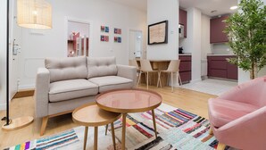 Un salon moderne avec un canapé, deux tables rondes, une lampe sur pied et un tapis coloré.