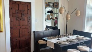 Un'area pranzo con un tavolo di legno e panche, una panca di legno scuro, uno specchio e un lampadario.