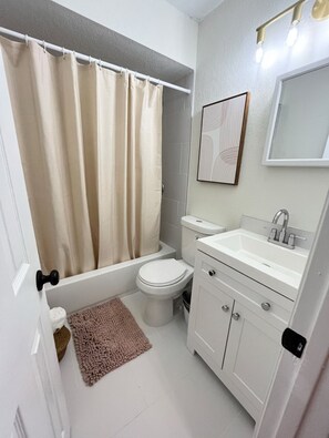 A compact bathroom with a bathtub, toilet, and sink. - Boho-Inspired Retreat • Close to Downtown & Ybor (Tampa)