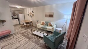 A modern living room with a sofa, coffee table, and a dining area with chairs.