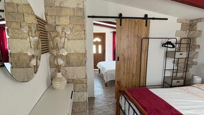 A bedroom with a stone wall, a wooden bed frame, a mirror, and a bedside table. - Beautiful home in Trogir (Trogir)