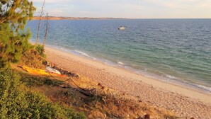 Een strand met een kajak en een boot op het water.