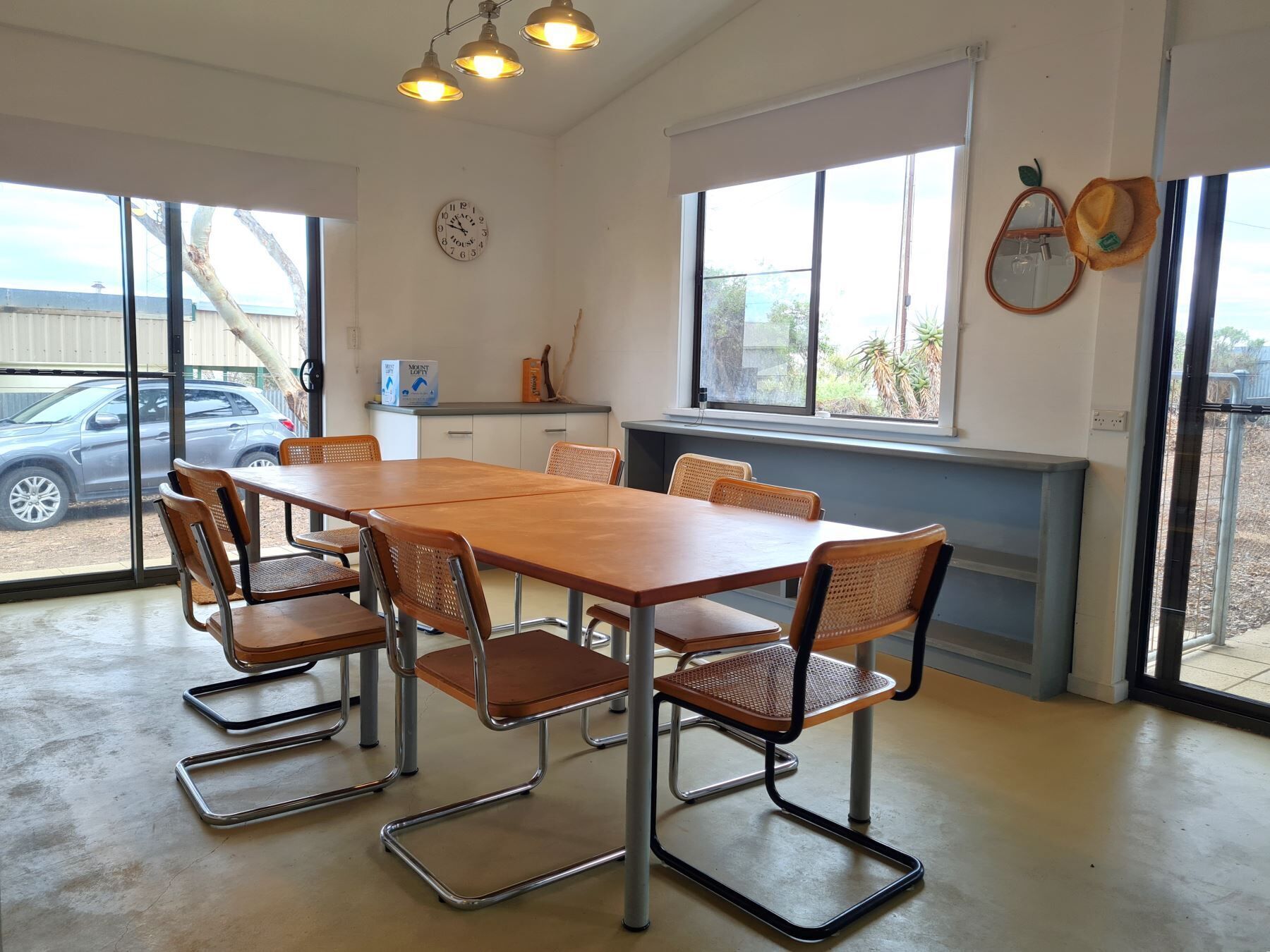 A dining area with a long wooden table and six metal-framed chairs.