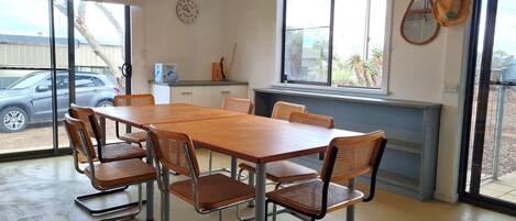 A dining area with a long wooden table and six metal-framed chairs.