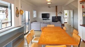 A spacious living area with a long wooden table and wicker chairs, a grey sofa, a television, and a fireplace. - Brooksea at Balgowan, Balgowan (Balgowan)