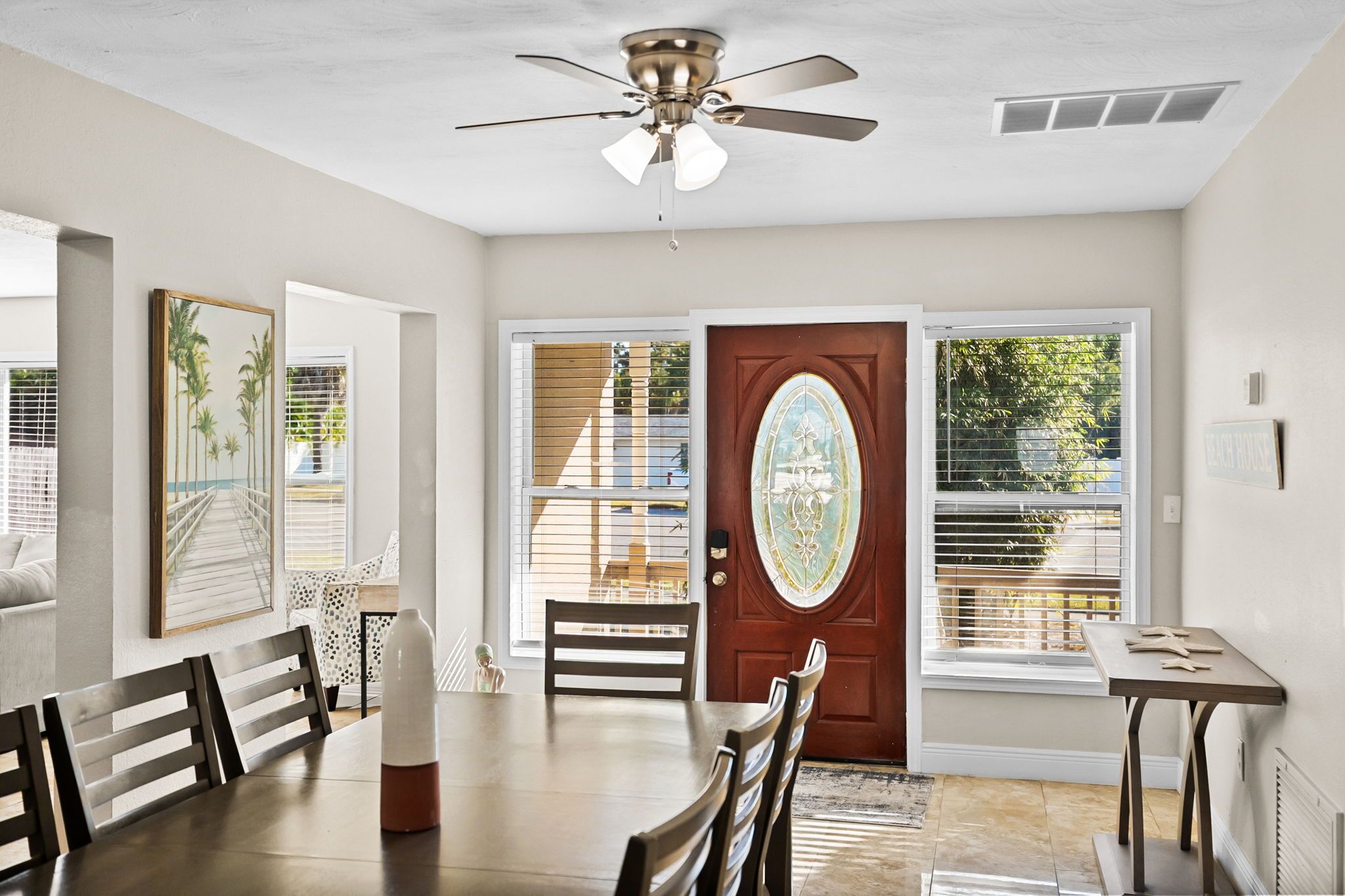 A dining area with a wooden table and chairs, a ceiling fan, and a door with a decorative glass panel.