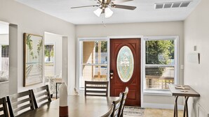 A dining area with a wooden table and chairs, a ceiling fan, and a door with a decorative glass panel.