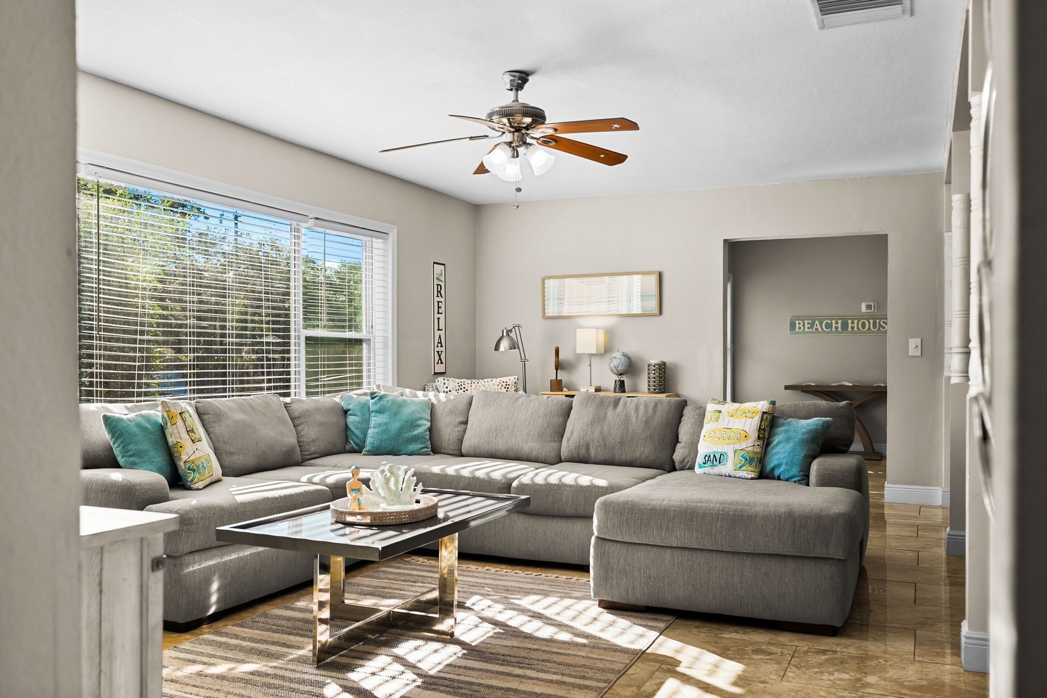 A living room with a sectional sofa, a coffee table, and a ceiling fan.