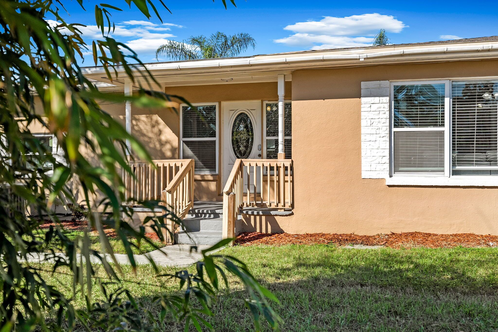A single-story house with a front porch, a door with a glass panel, and a window with shutters.