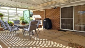 Eine Terrasse im Freien mit Tisch und Stühlen, einem Grill und einer Backsteinmauer.