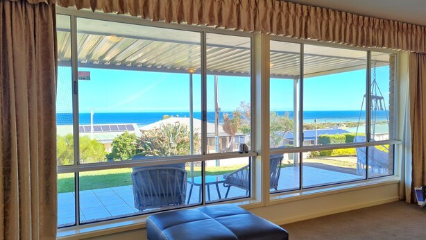 Una habitación con ventanas amplias que dan a una vista del océano y un patio amoblado.