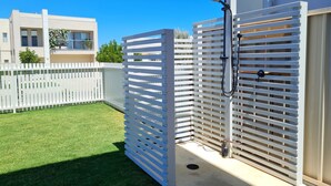 A modern outdoor shower area with a white fence, a concrete floor, and a clear blue sky. - Jetty Nights, Port Hughes (Port Hughes)