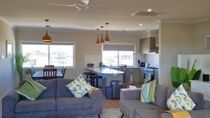 Una sala de estar moderna con dos sofás grises, un comedor y una cocina con una isla central.