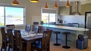 Una cocina moderna con una isla central, taburetes de bar y una mesa de comedor con sillas.
