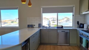 Una cocina moderna con una isla grande, electrodomésticos integrados y ventanas amplias con vistas al vecindario.