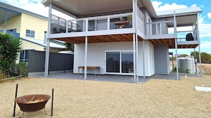 Une maison à deux étages dotée d’un balcon, d’une terrasse couverte et d’une allée gravillonnée.