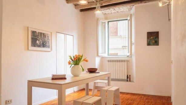 A dining area with a table, chairs, and a vase with flowers. - Casa Cristina in Piazza Farnese (Rome)