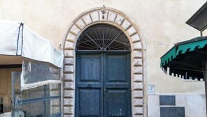 A building with a large, dark blue door framed by a stone archway. - Casa Cristina in Piazza Farnese (Rome)