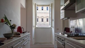 A modern kitchen with a large window, stainless steel appliances, and a wooden floor. - Casa Cristina in Piazza Farnese (Rome)