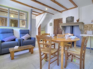 Ein gemĂŒtliches Wohnzimmer mit einem blauen Sofa, einem Holzespeisetisch und StĂŒhlen, einem Kamin und einer Treppe, die in einen anderen Raum fĂŒhrt.