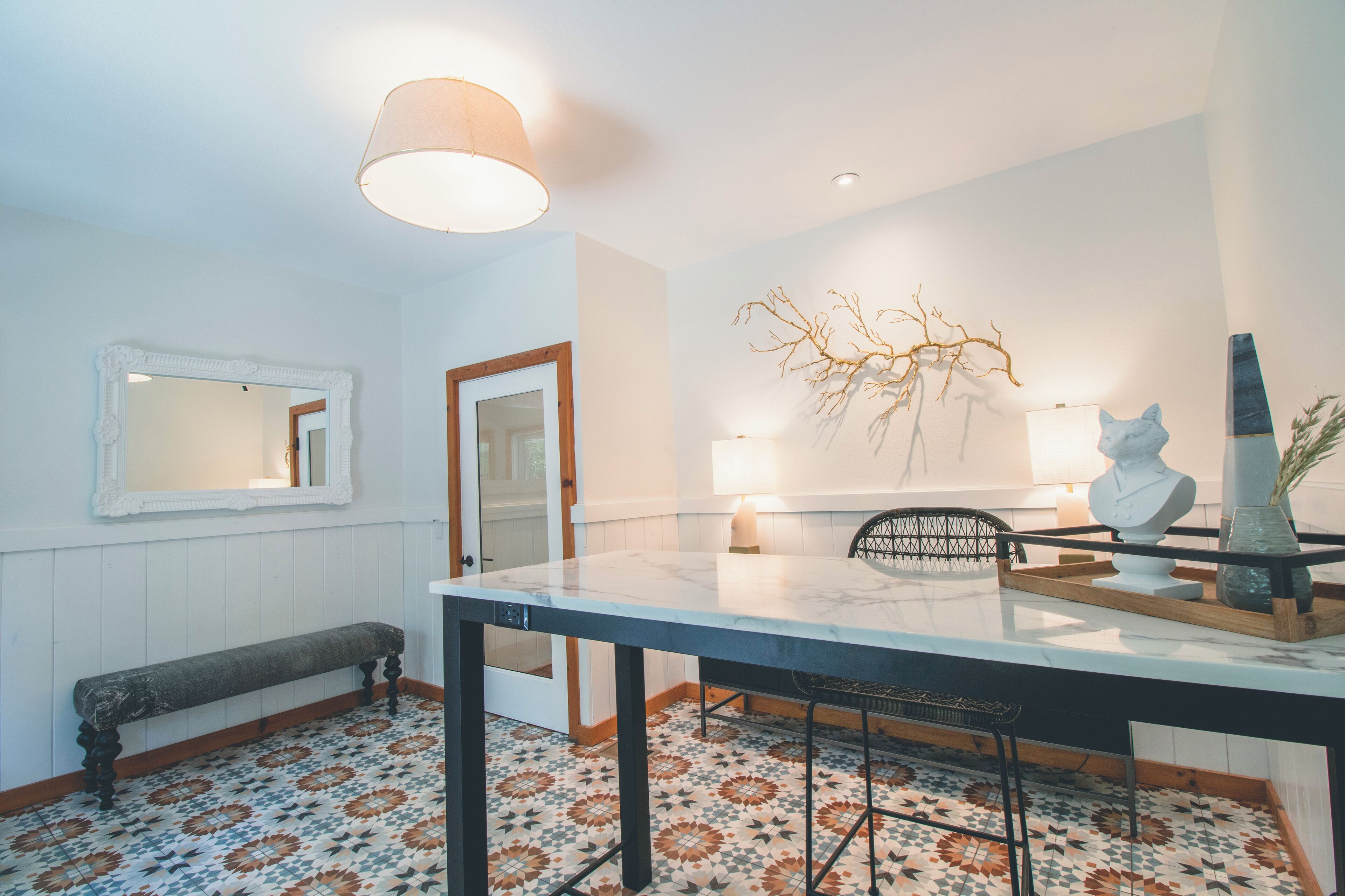 A dining area with a marble table, bench, and patterned floor tiles.