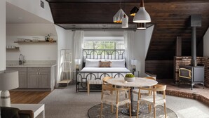 A bedroom with a bed, bedside table, lamp, and a window. - Harvey House (Idyllwild)