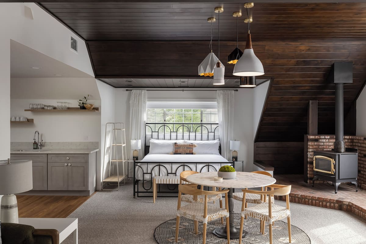 A bedroom with a bed, bedside table, lamp, and a window.