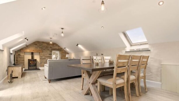 An attic room with a dining table, chairs, a sofa, and a fireplace. - Awel y Môr - 3 Bedroom Cottage - Whitesands (Saint Davids)