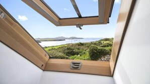 A view through a skylight with a clear sky, a body of water, and distant landforms. - Awel y Môr - 3 Bedroom Cottage - Whitesands (Saint Davids)