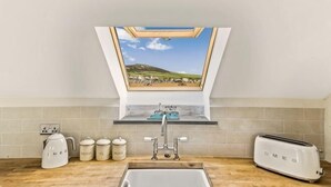 A kitchen with a skylight, a sink, a toaster, and jars on the counter. - Awel y Môr - 3 Bedroom Cottage - Whitesands (Saint Davids)