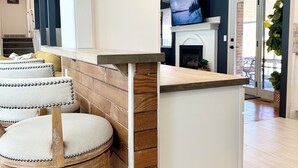 Een moderne keuken met houten barstoelen, een vast kookeiland en een open haard.