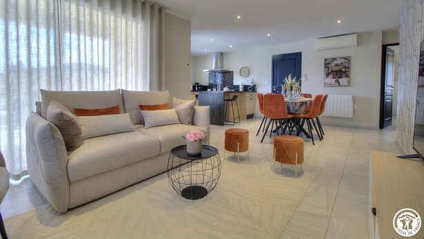 A modern living room with a sofa, coffee table, and dining area.