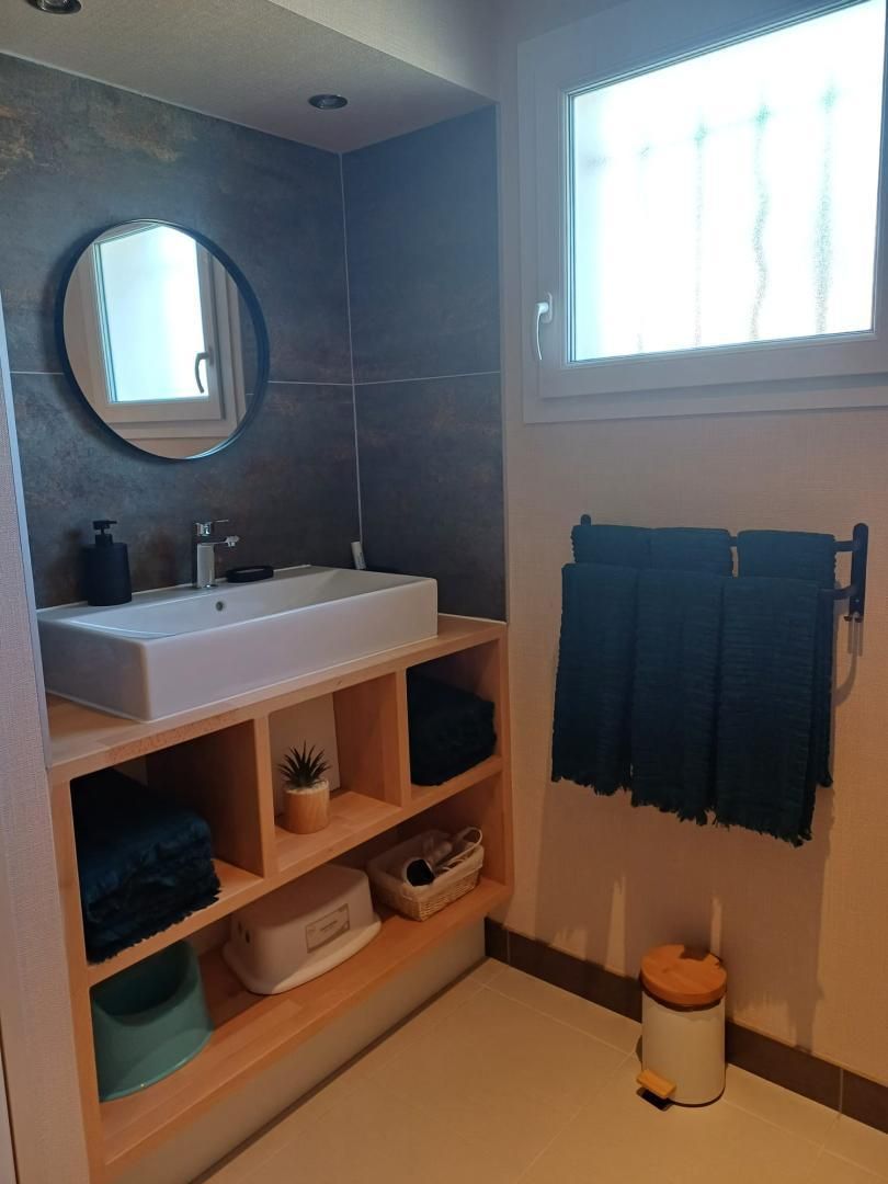 Un baño moderno con un lavamanos grande, un espejo y una ventana que deja entrar luz natural.