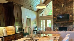 Una cocina amplia con una isla grande, armarios de madera oscura y una chimenea de piedra.