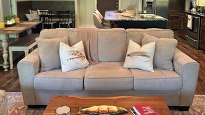 Amplia sala de estar con techo alto y de madera, zona de comedor con mesa y sillas, y cocina equipada con electrodomésticos modernos.