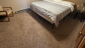 A bedroom with a bed, a chair, a ceiling fan, and a wall with three framed pictures. - Rustic Ridge (Gregory)