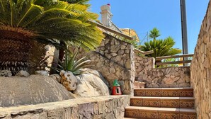 A stone staircase with decorative patterns, leading up to a stone wall with a statue on top.