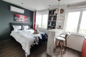 Un dormitorio con cama, mesita de noche, ventana y estantería.