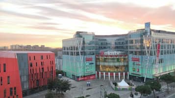 A modern building with a glass facade, a prominent sign, and a red structure to the left.