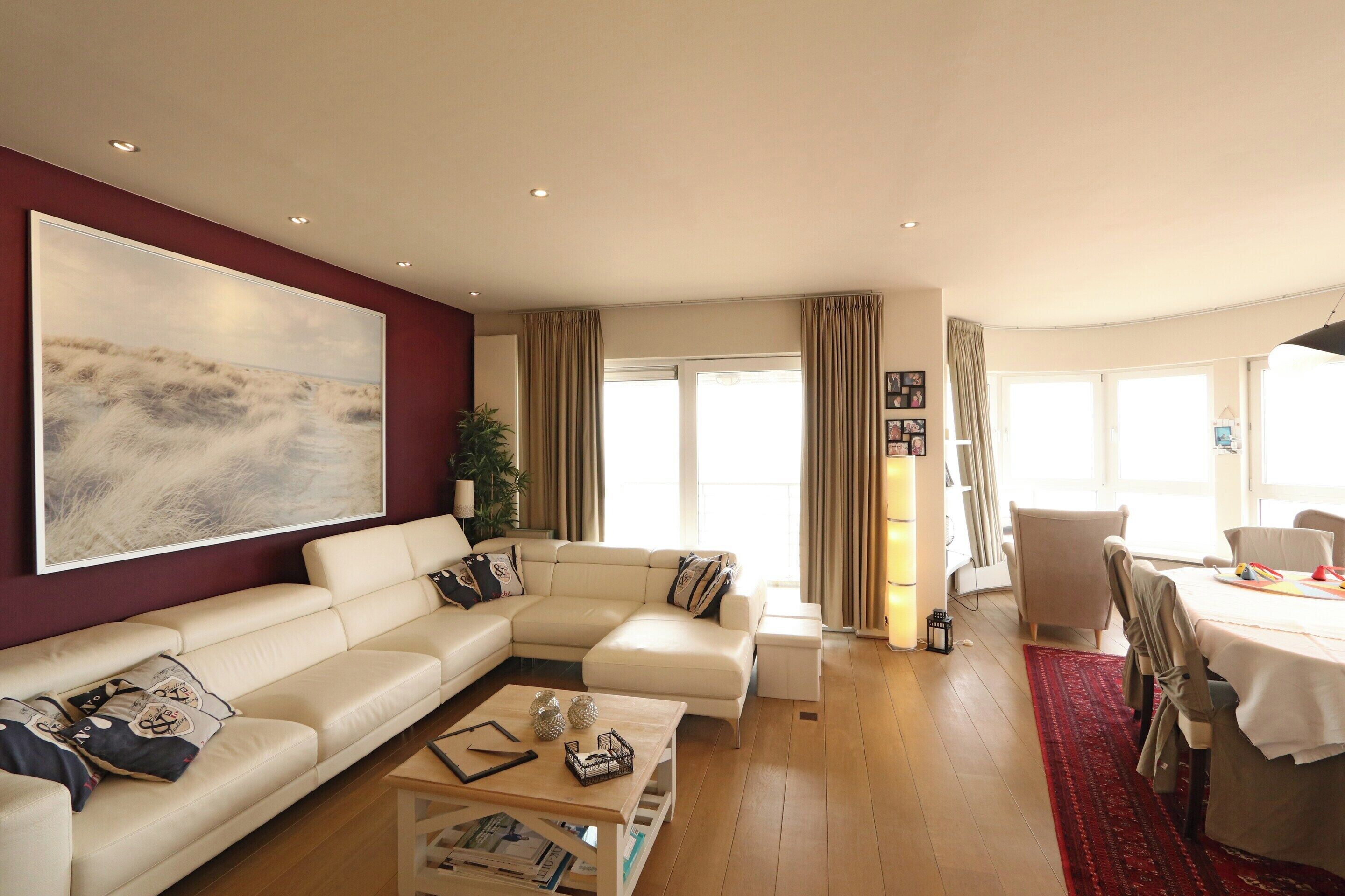 A modern living room with a sectional sofa, a coffee table, and a dining area with a table and chairs.