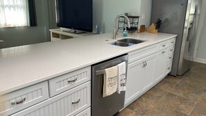 Una cocina moderna con una isla central, electrodomésticos de acero inoxidable y armarios blancos.