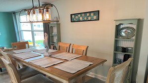 Comedor con una mesa de madera, seis sillas y una lámpara decorativa colgante.