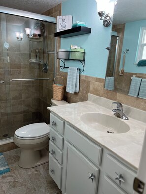 A bathroom with a shower, toilet, vanity, and a "No Wake Zone" sign. - 2 Bedroom, 2 1/2 Bath Waterfront Home. Kayaks. Dogs welcome (Hudson)