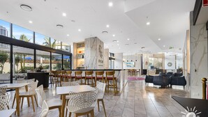 Un espace de restauration intérieur moderne, doté d’un sol en marbre, de chaises en bois et blanches, et d’un bar avec un comptoir en marbre.