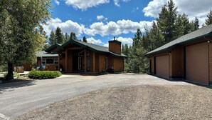 Eine Lodge mit überdachter Veranda, einem Schotterweg und bewaldeter Umgebung.