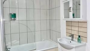 A bathroom with a glass shower enclosure, a white sink, and a cabinet with a mirror. - Warmley Flat by Pulse Properties - close to Bristol Centre, Bath and Cotswolds. (Warmley)