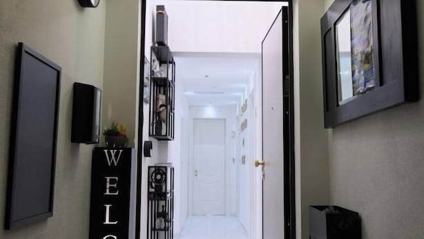 A hallway with a 'WELCOME' sign, a black shelf with various items, and a framed picture on the wall. - Ok Home Pescara Rooms (Pescara)