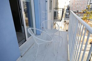 A balcony with white metal chairs and a glass door. - Ok Home Pescara Rooms (Pescara)