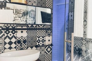 A bathroom with patterned tiles, a white sink, and a blue door. - Ok Home Pescara Rooms (Pescara)